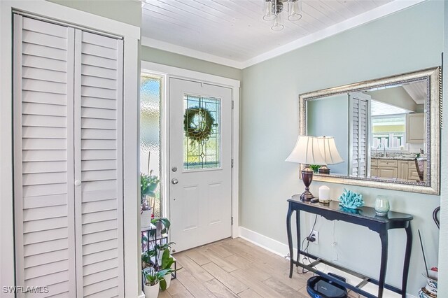 entryway featuring light wood-style floors, a healthy amount of sunlight, ornamental molding, and baseboards