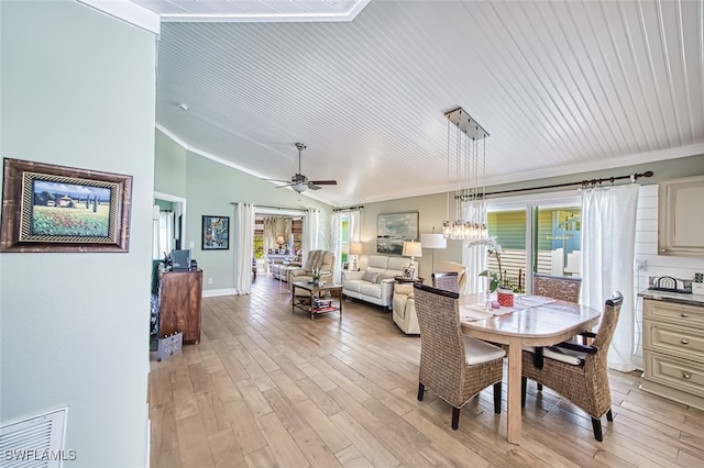 dining area with light wood-style floors, lofted ceiling, ornamental molding, and a ceiling fan