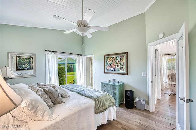 bedroom with high vaulted ceiling, multiple windows, crown molding, and wood finished floors