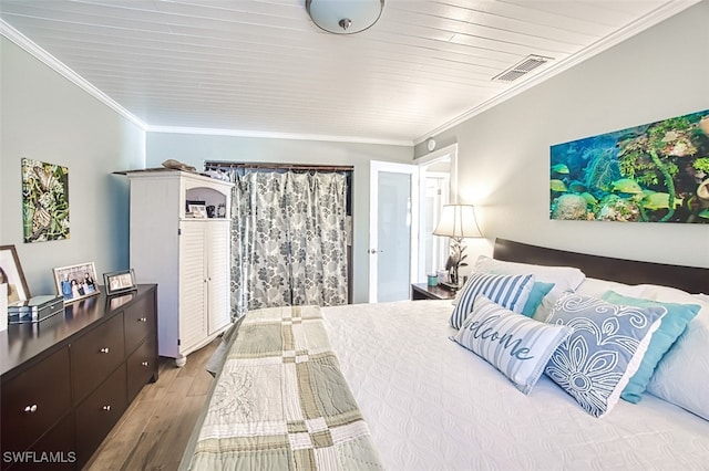 bedroom featuring crown molding, visible vents, and wood finished floors