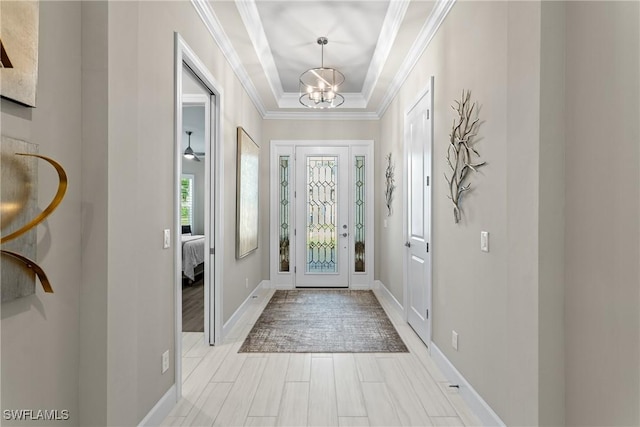 foyer entrance with baseboards, light wood-style floors, a chandelier, and crown molding