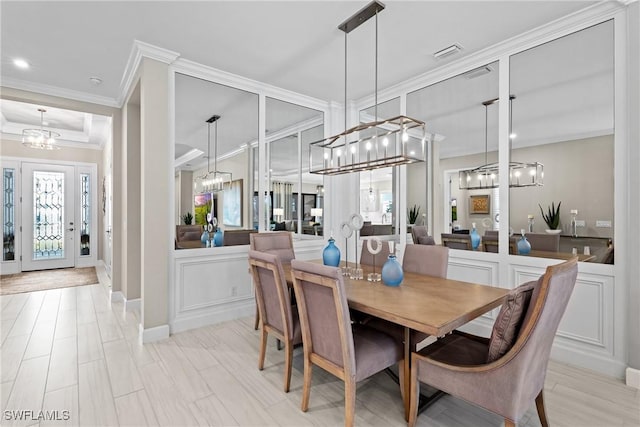 dining space with a chandelier, visible vents, crown molding, and a decorative wall
