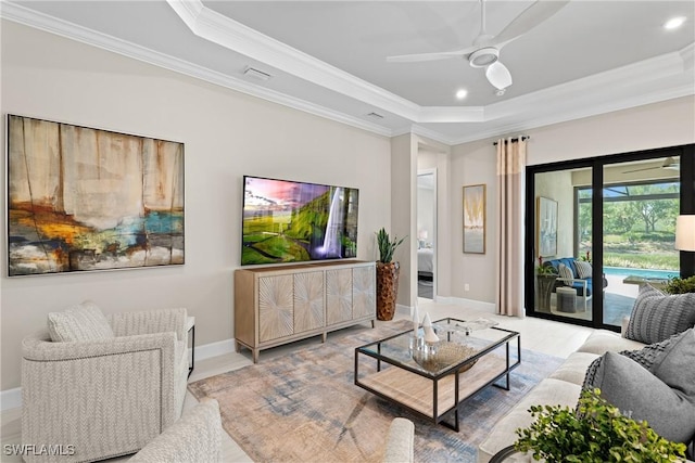 living room with a ceiling fan, baseboards, recessed lighting, crown molding, and a raised ceiling