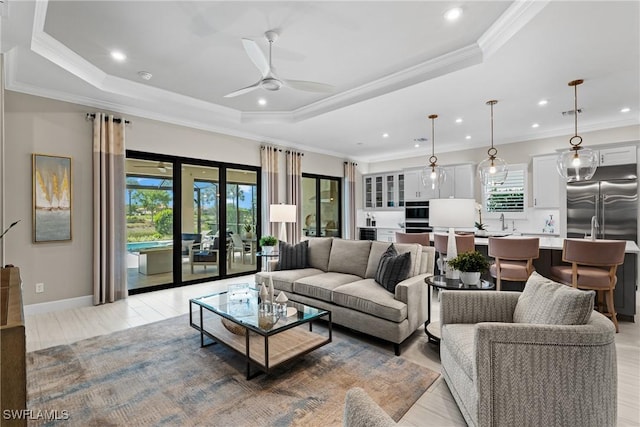 living room featuring ornamental molding, recessed lighting, a ceiling fan, and a raised ceiling
