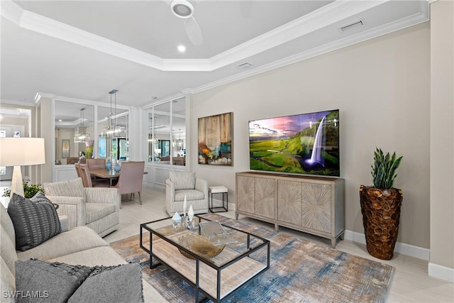 living room with ceiling fan, baseboards, visible vents, a raised ceiling, and crown molding