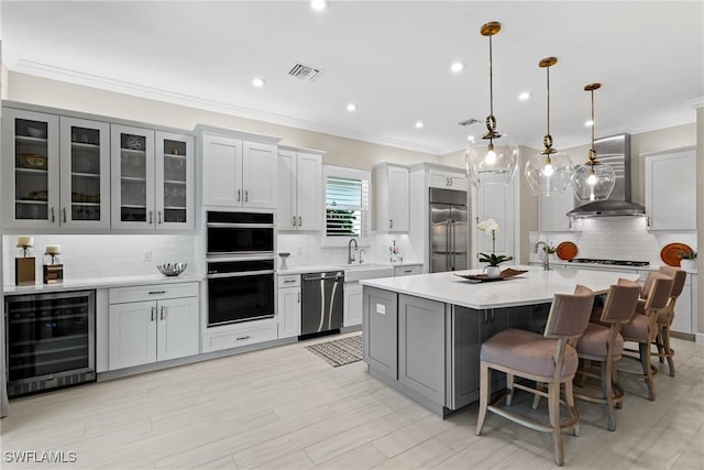 kitchen featuring wall chimney range hood, beverage cooler, visible vents, stainless steel appliances, and backsplash