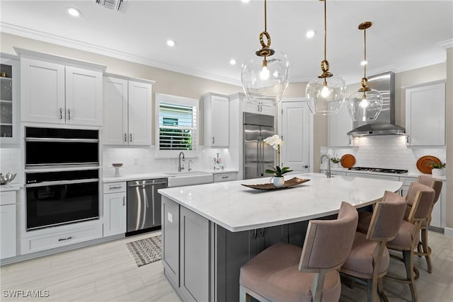 kitchen with crown molding, wall chimney exhaust hood, appliances with stainless steel finishes, and a sink