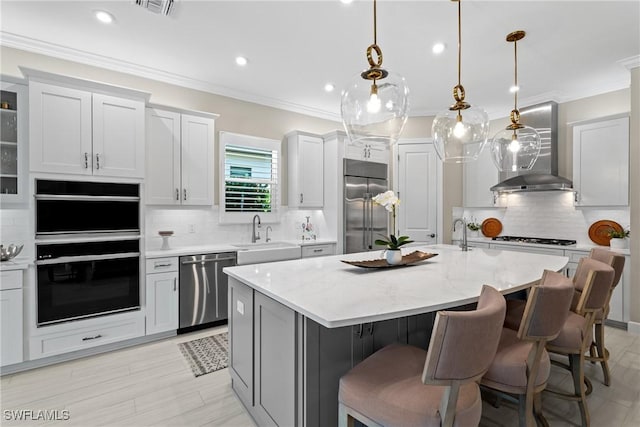 kitchen featuring ornamental molding, wall chimney exhaust hood, appliances with stainless steel finishes, and a sink