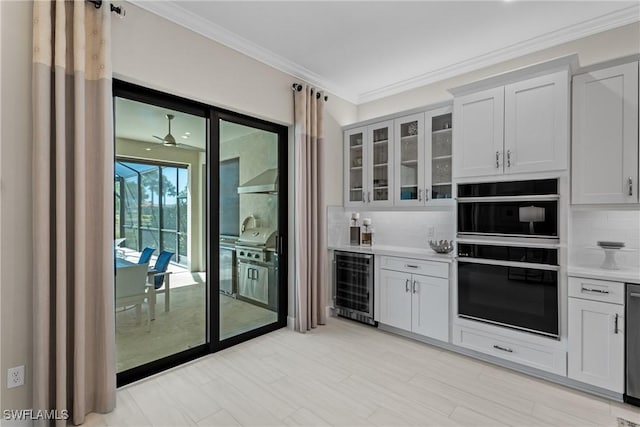 kitchen with backsplash, glass insert cabinets, wine cooler, ornamental molding, and dobule oven black