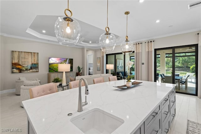 kitchen featuring open floor plan, visible vents, ornamental molding, and a sink