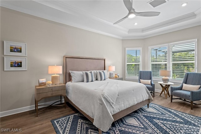 bedroom with a tray ceiling, crown molding, visible vents, baseboards, and wood finished floors