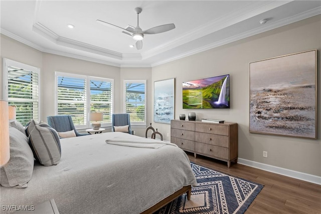 bedroom featuring a raised ceiling, crown molding, a ceiling fan, baseboards, and wood finished floors