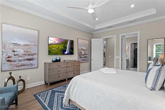 bedroom featuring a raised ceiling, ornamental molding, and wood finished floors