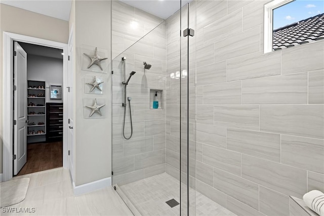 bathroom with a spacious closet and a stall shower