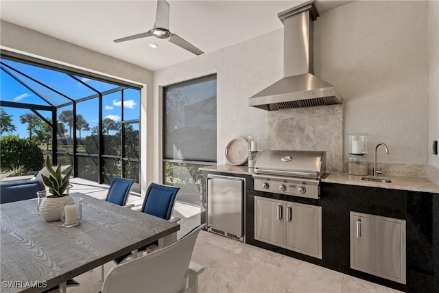 kitchen with ceiling fan, wall chimney range hood, a sunroom, stainless steel refrigerator, and a sink