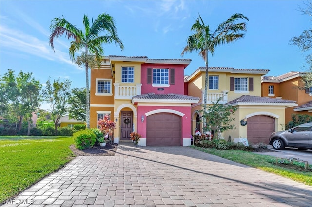 mediterranean / spanish house with a tile roof, a front yard, decorative driveway, and stucco siding