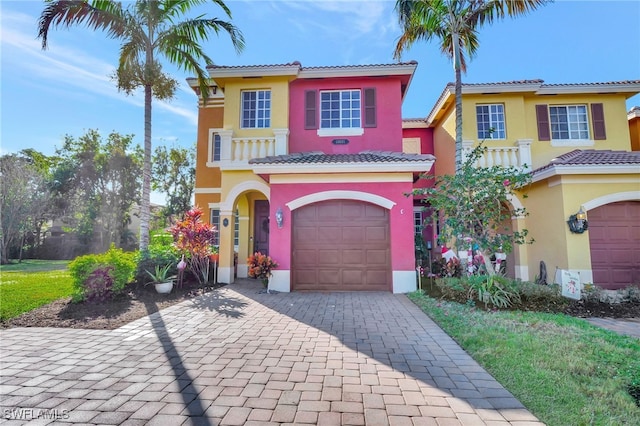 mediterranean / spanish home with a garage, decorative driveway, a tiled roof, and stucco siding