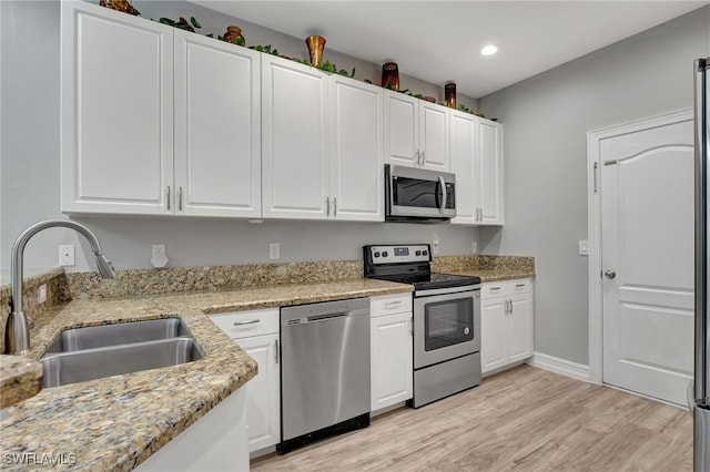 kitchen with stainless steel appliances, white cabinetry, and a sink