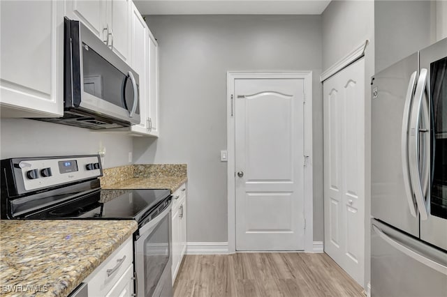 kitchen with stainless steel appliances, white cabinetry, light wood finished floors, and light stone counters