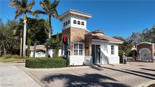 view of front of house with stone siding, a tiled roof, and stucco siding