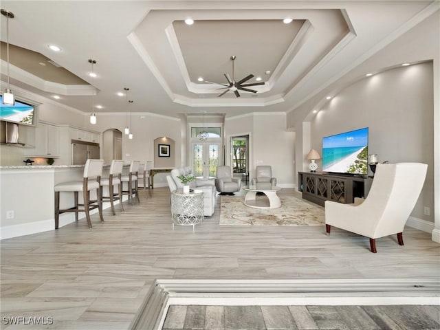 living room featuring a raised ceiling, crown molding, baseboards, and ceiling fan