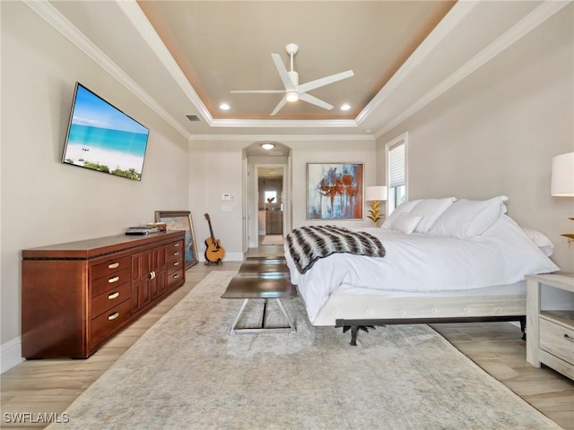 bedroom featuring a tray ceiling, arched walkways, visible vents, light wood-style floors, and ornamental molding