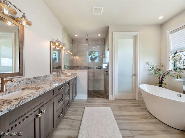 full bathroom featuring double vanity, a freestanding tub, a shower stall, and a sink