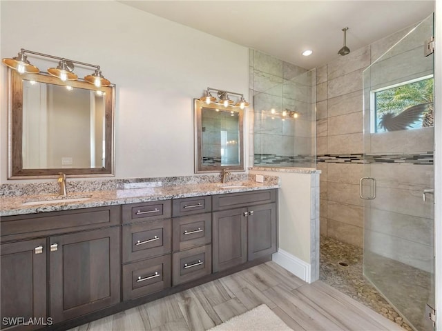 bathroom with double vanity, a stall shower, and a sink