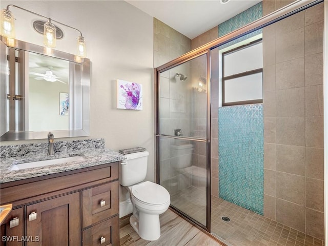 bathroom with toilet, a shower stall, a ceiling fan, and vanity