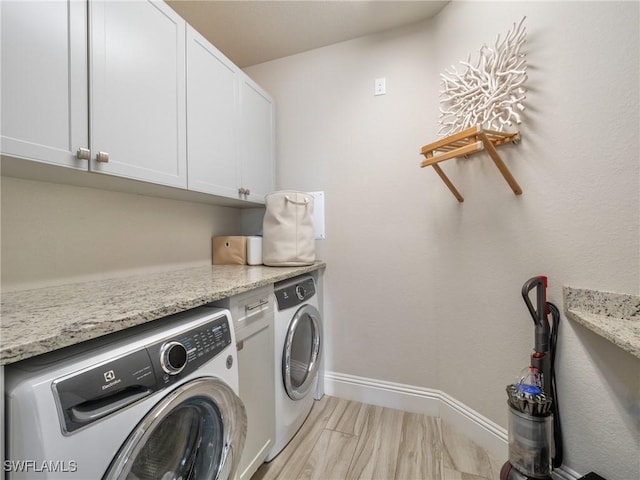 laundry area featuring separate washer and dryer, cabinet space, and baseboards