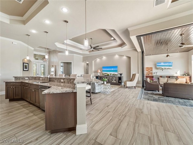 kitchen featuring a raised ceiling, ceiling fan, open floor plan, stainless steel dishwasher, and a sink