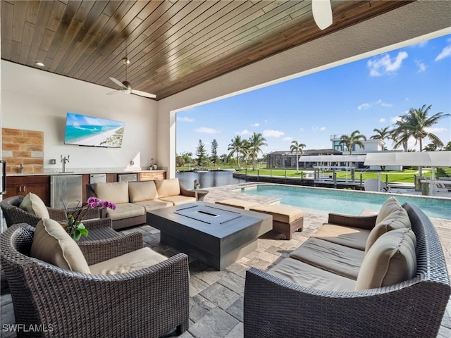 view of patio featuring an outdoor pool, ceiling fan, an outdoor hangout area, exterior kitchen, and a sink