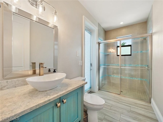 bathroom featuring a shower stall, toilet, and vanity