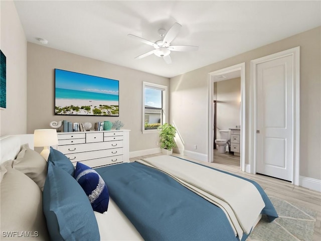 bedroom with ensuite bathroom, light wood-type flooring, a ceiling fan, and baseboards