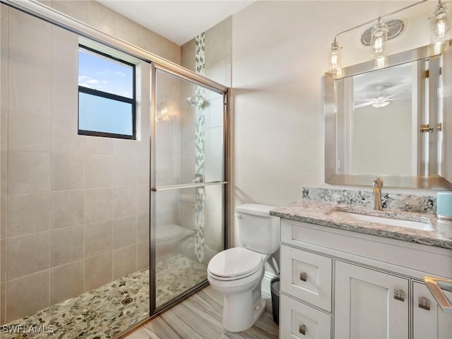 full bath with ceiling fan, tiled shower, vanity, and toilet