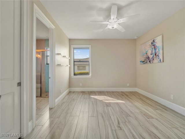 unfurnished room featuring wood tiled floor, baseboards, and ceiling fan