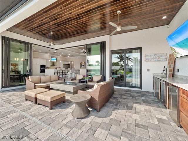 view of patio with ceiling fan, exterior kitchen, and an outdoor living space with a fire pit