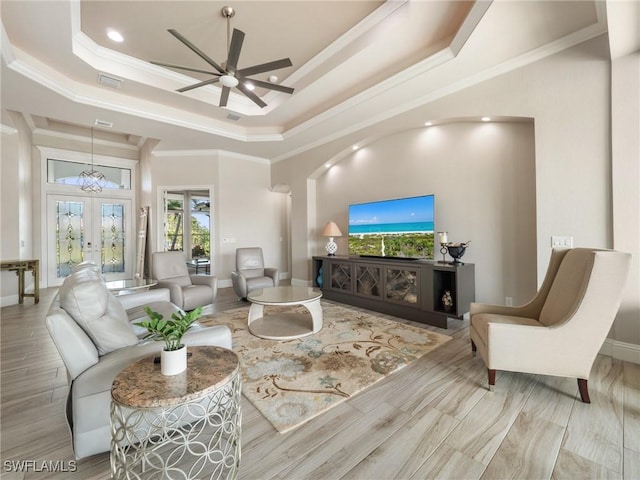 living room featuring a tray ceiling, french doors, crown molding, visible vents, and wood finished floors