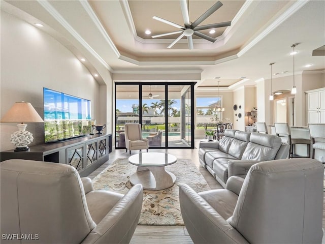 living room featuring wood finished floors, ornamental molding, a raised ceiling, and a ceiling fan