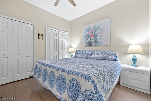 bedroom with ceiling fan, wood finished floors, and two closets