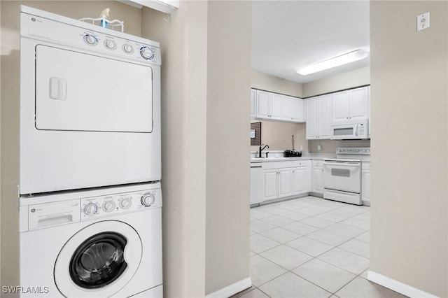 clothes washing area with light tile patterned floors, stacked washer and dryer, a sink, laundry area, and baseboards