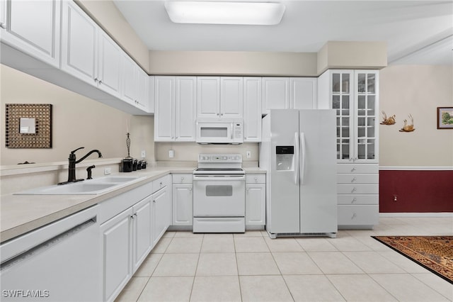 kitchen with white appliances, glass insert cabinets, light countertops, white cabinetry, and a sink