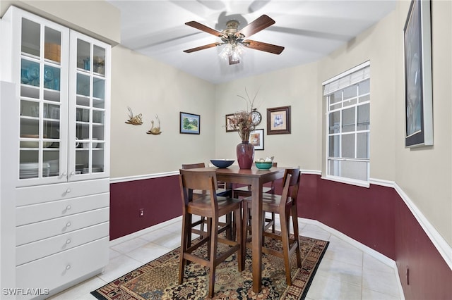 dining room with light tile patterned floors, a ceiling fan, and baseboards