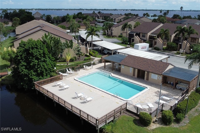 community pool featuring a residential view, a patio area, a water view, and fence