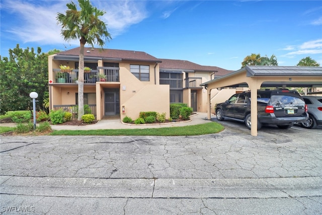 townhome / multi-family property featuring covered and uncovered parking, a balcony, and stucco siding