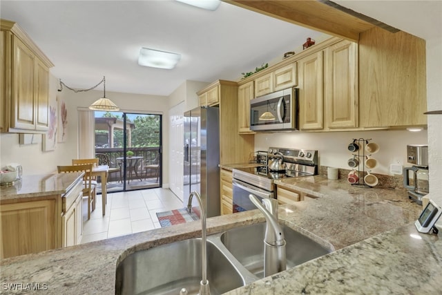 kitchen featuring appliances with stainless steel finishes, a sink, light stone countertops, and pendant lighting