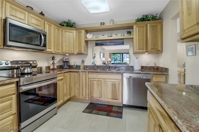 kitchen featuring appliances with stainless steel finishes, dark stone countertops, light brown cabinets, open shelves, and a sink