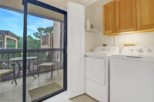 laundry room with cabinet space, light tile patterned floors, and washer and clothes dryer