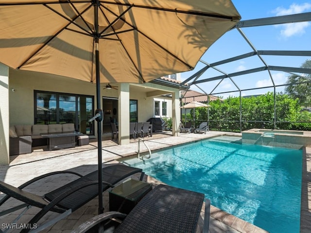 view of pool with a patio, a pool with connected hot tub, a ceiling fan, glass enclosure, and an outdoor living space