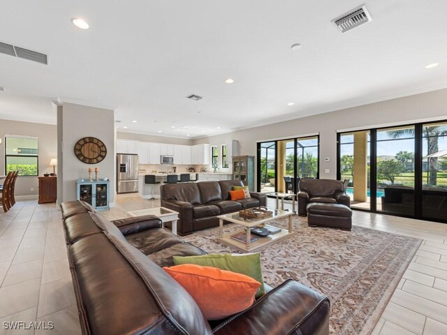 living area with ornamental molding, recessed lighting, and visible vents